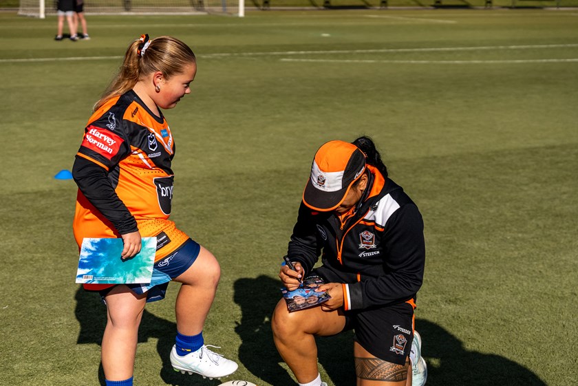 Sarah Togatuki signs some items for a young fan.