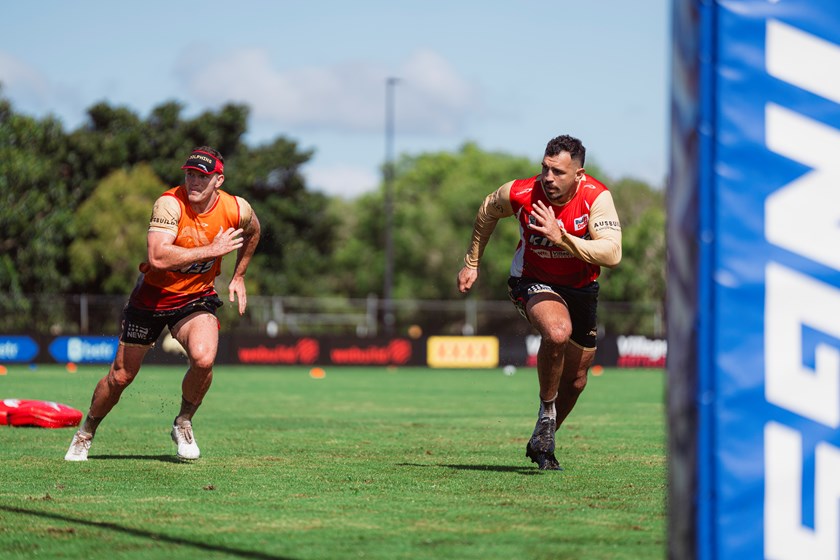 Josh Kerr runs alongside Tom Gilbert at Dolphins training.